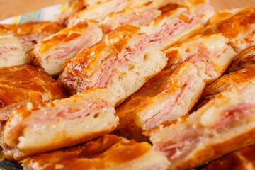 Piccole pizzette di pasta sfoglia ripiene di mozzarella e prosciutto cotto pronte per un buffet 
