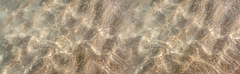 Ocean water texture background. Sandy sea bottom overhead, banner. Shallow water surface