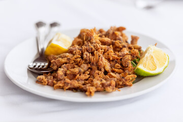 Traditional mediterranean snack Moscardini deep fried small cuttlefish o squid (baby octopus) with a slice of lemon
