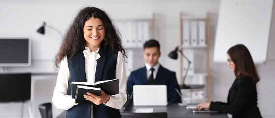 Pretty young businesswoman with notebooks during meeting in office