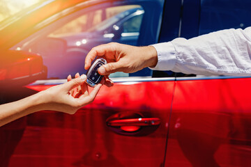 Men taking keys from the car from the hand of salesperson or car rental worker.