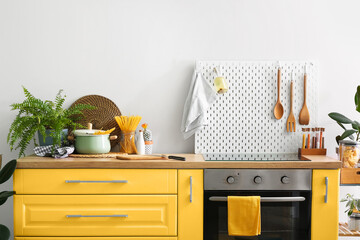 Interior of modern kitchen with yellow furniture, oven and peg board - obrazy, fototapety, plakaty