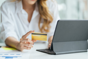 Young woman holding credit card and using laptop computer. Girl working online. Online shopping, e-commerce, internet banking, spending money, working from home concept