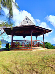 Traditional Caribbean gazebo. Wooden pergola in French West Indies garden under tropical blue sky....