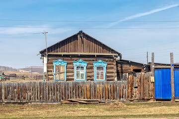 Fototapeta na wymiar Old wooden rickety house with blue architraves in the village