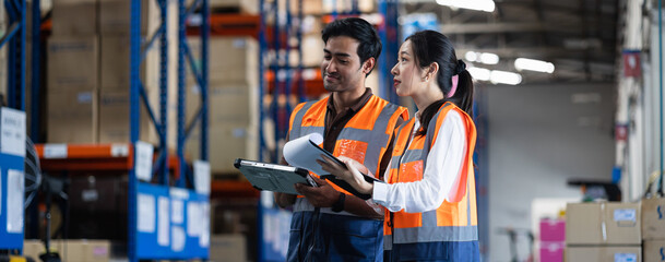 Panoramic warehouse worker and manager checks stock and inventory with digital tablet computer in...