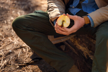 Male tourist cutting apple in forest, closeup