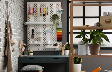 Stylish decorator's workplace with modern tools and shelf unit in workshop