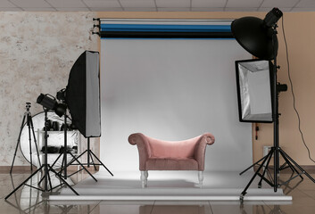 Lighting equipment, armchair and cyclorama in modern photo studio
