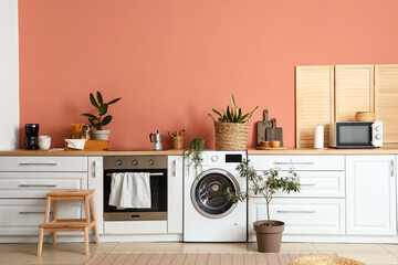 Stylish interior of kitchen with modern washing machine