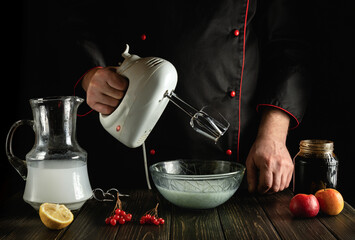 Chef uses a hand-held electric mixer to prepare a delicious smoothie with fruits and milk. Menu idea for a restaurant or hotel
