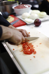 chef picando tomate con un cuchillo en tabla de cocinar