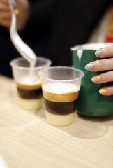 elaboración de café bombón barraquito con licor y mano con manicura de camarera