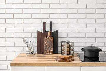 Cutting boards and kitchen utensils on counter near white brick wall