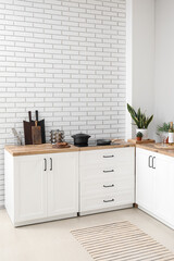 Interior of light kitchen with cutting boards, utensils and stove