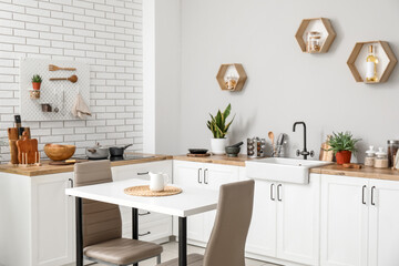 Interior of light kitchen with dining table, counters and utensils