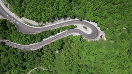 Aerial view of winding road from the high mountain pass. Great road trip trough the dense woods....