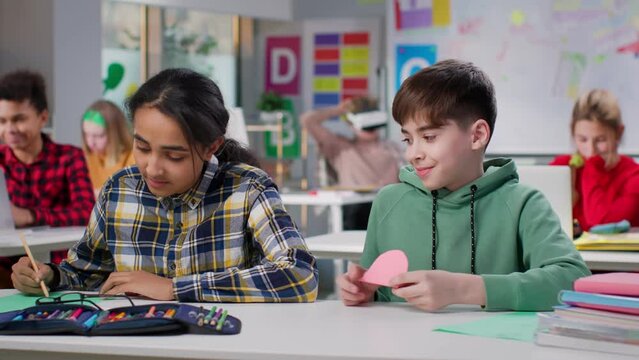 Shy teen boy giving heart note to classmate