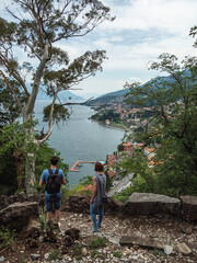 Two hikers stop on the path to look at the view of Lake Como