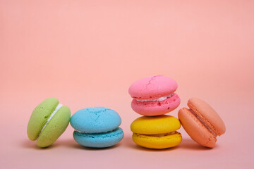 Colorful and bright French macarons cookies on pink background.