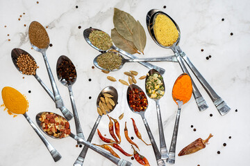 Various herbs and spices for cooking. Spices in spoons are scattered on a white background, top...