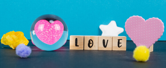 reflet de coeur dans une bille en verre avec love écrit sur des cubes de bois et pompons colorés