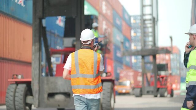 Two Caucasian cargo container works enjoy to work in workplace and sometime use walkie talkie to contack with their team.