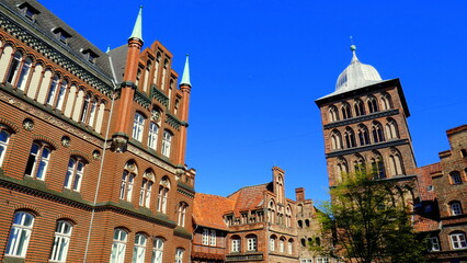 prunkvolle alte Backsteinhäuser in der Altstadt von Lübeck und hohem Burgtorturm unter blauem...