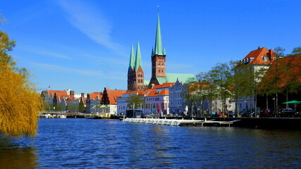 Fototapeta premium malerische historische Häuser entlang der Trave in Lübeck und Türme von St. Petri und St. Marien