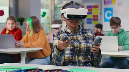 Teen girl student using vr headset and remote controllers in classroom. Modern technologies in educational process. Schoolgirl study in virtual reality goggles. 