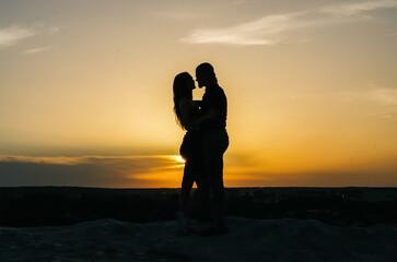 Fototapeta premium silhouette of a loving couple embracing at sunset