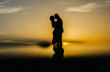 silhouette of a loving couple embracing at sunset