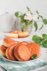 Pile of fresh golden donuts on a wite plate. Sweet breakfast with doughnuts.