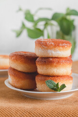 Stacked fresh donuts with mint on a plate on a yellow tablecloth.