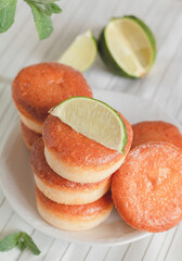 Stacked fresh donuts with lime and mint on a table. Sweet breakfast with golden doughnuts. Top view.