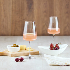 Glasses of pink wine and snacks for romantic dinner on table