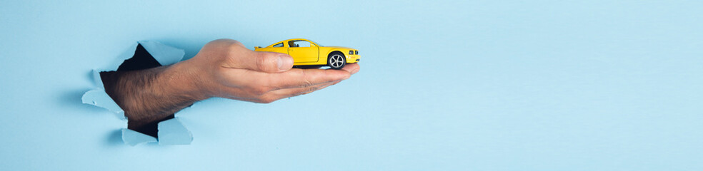 hand of man hold miniature toy cars on the blue background
