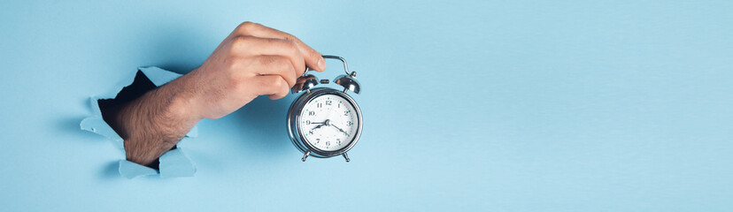 A man hand holds a vintage alarm clock