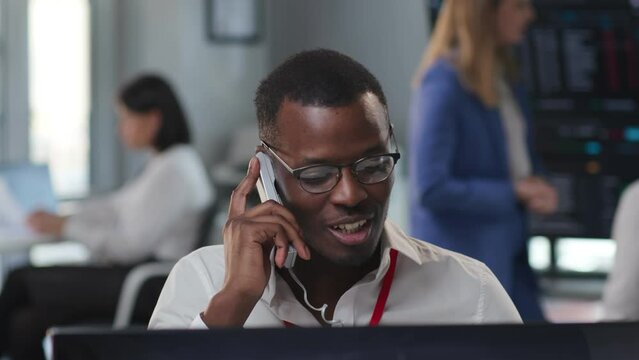 Smiling African American consultant talking to client on phone working in call center
