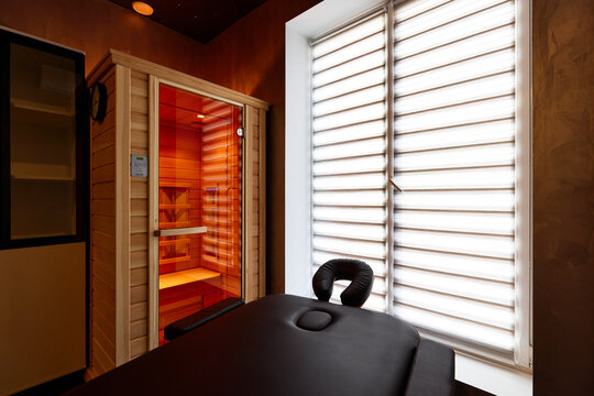 Massage bed and cabinet with red light near window in office
