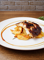 Baked cod, halibut, fillet of white fish. Fish with baked potato slices with lemon and rosemary herbs sauce on a white plate. Serving dishes in the restaurant. Lunch, dinner. Photos for the menu.