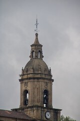 Fototapeta na wymiar church dome in northern spain with clock in front with cloudy sky on spring day