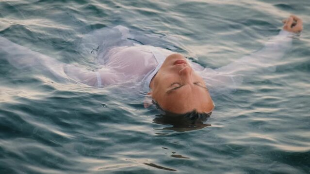 A young man lies on the water in the sea enjoying the coolness of the waves
