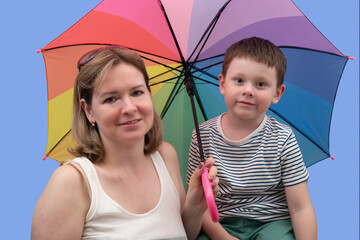 Portrait of a woman with a child with a multicolored umbrella on a blue background.