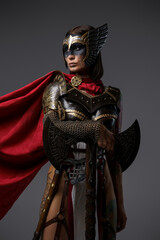 Shot of scandinavian warrior lady dressed in helmet and armor against grey background.