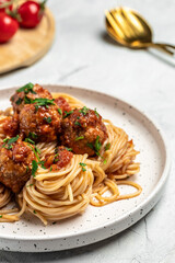 Meatballs served over italian spaghetti pasta with tomato sauce on a light background. Italian food. vertical image. top view. place for text