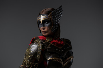 Shot of female warrior with painted face dressed in dark armor and red cape.