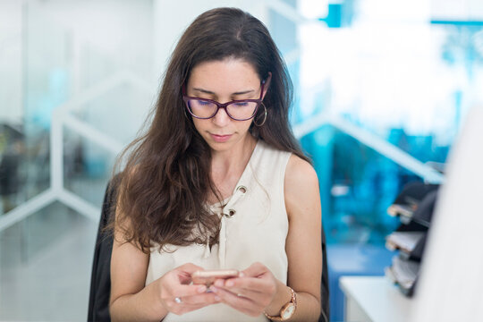 Young woman checking messages on the cell phone at work