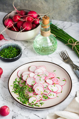 Fresh radish and green onion salad on a plate on the table. Home cooking. Vertical view
