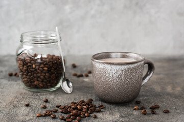 Latte in a ceramic cup and jar with coffee beans on the table. Time for a break and relaxation
